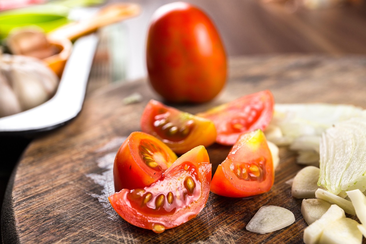 fresh Italian ingredients arranged on a wooden board including ripe tomatoes, basil, garlic, mozzarella, and olive oil