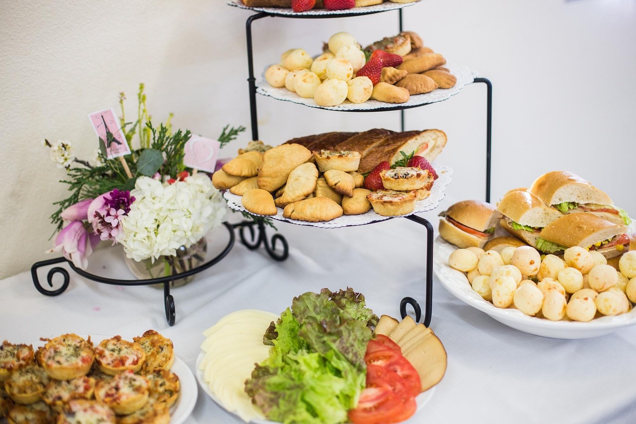 multiple catering platters with appetizers and foods arranged on a buffet table at an event