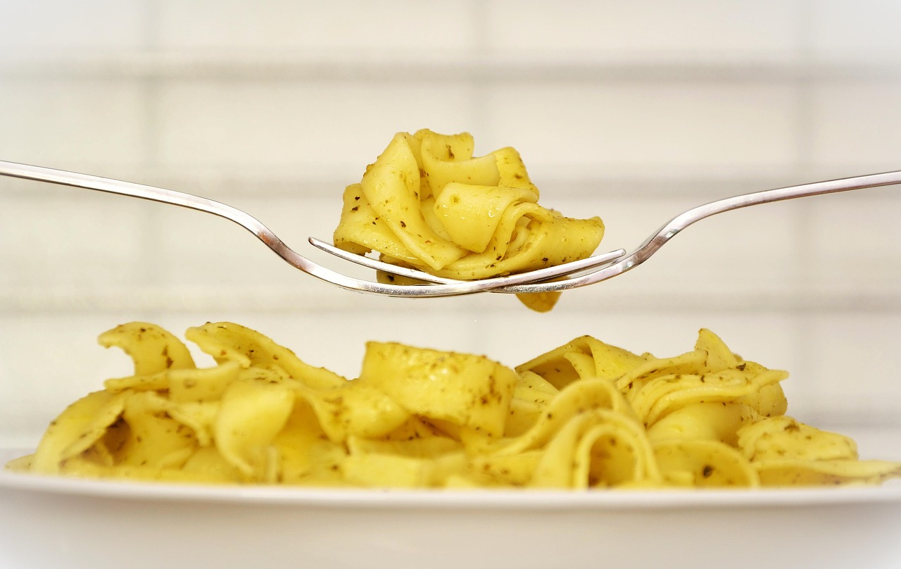 Chef's hands arranging a fresh pasta dish with basil